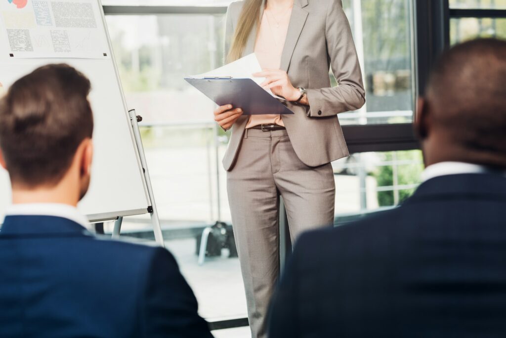 partial view of female educator with notepad and multiracial business colleagues on seminar in
